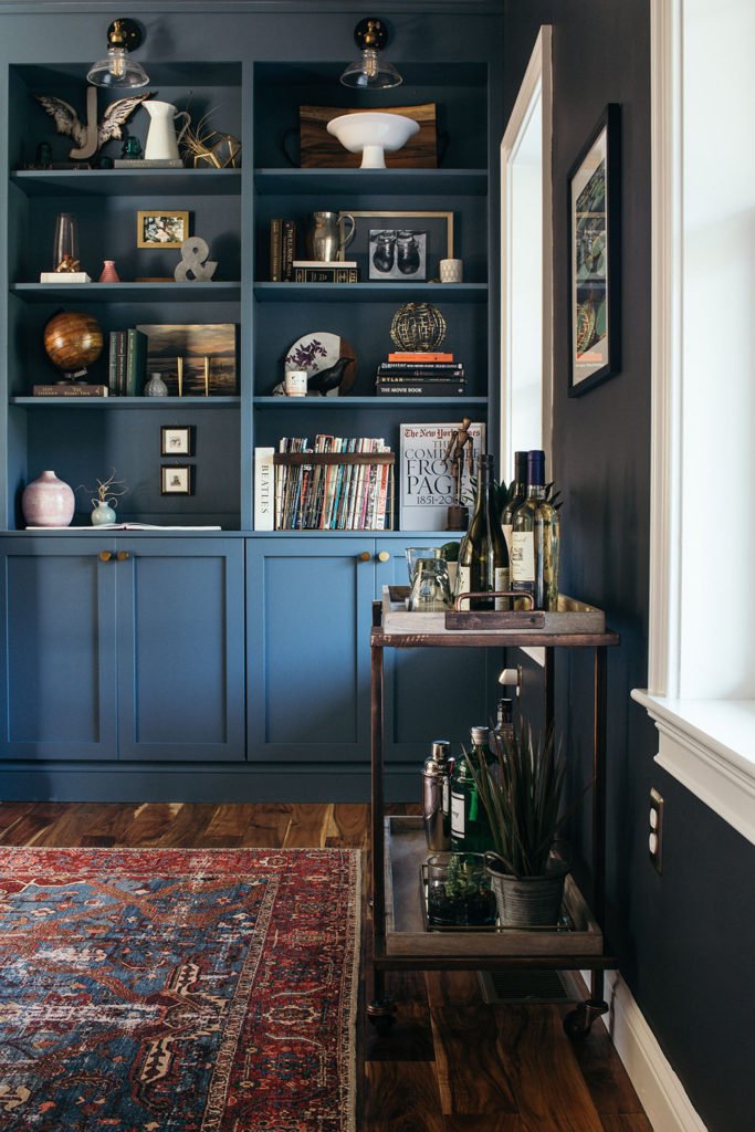 Blue built-in bookcase with bar cart in a moody library