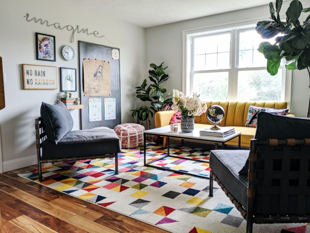 Yellow couch and gray chairs on colorful mosaic rug
