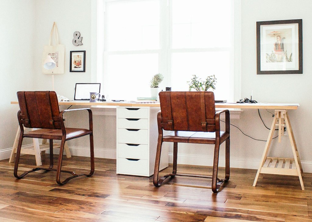 Long desk with two leather chairs in front of it.