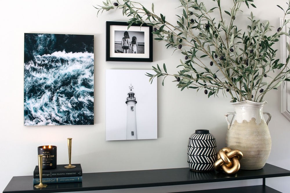 Olive branches on a modern entryway table with coastal artwork