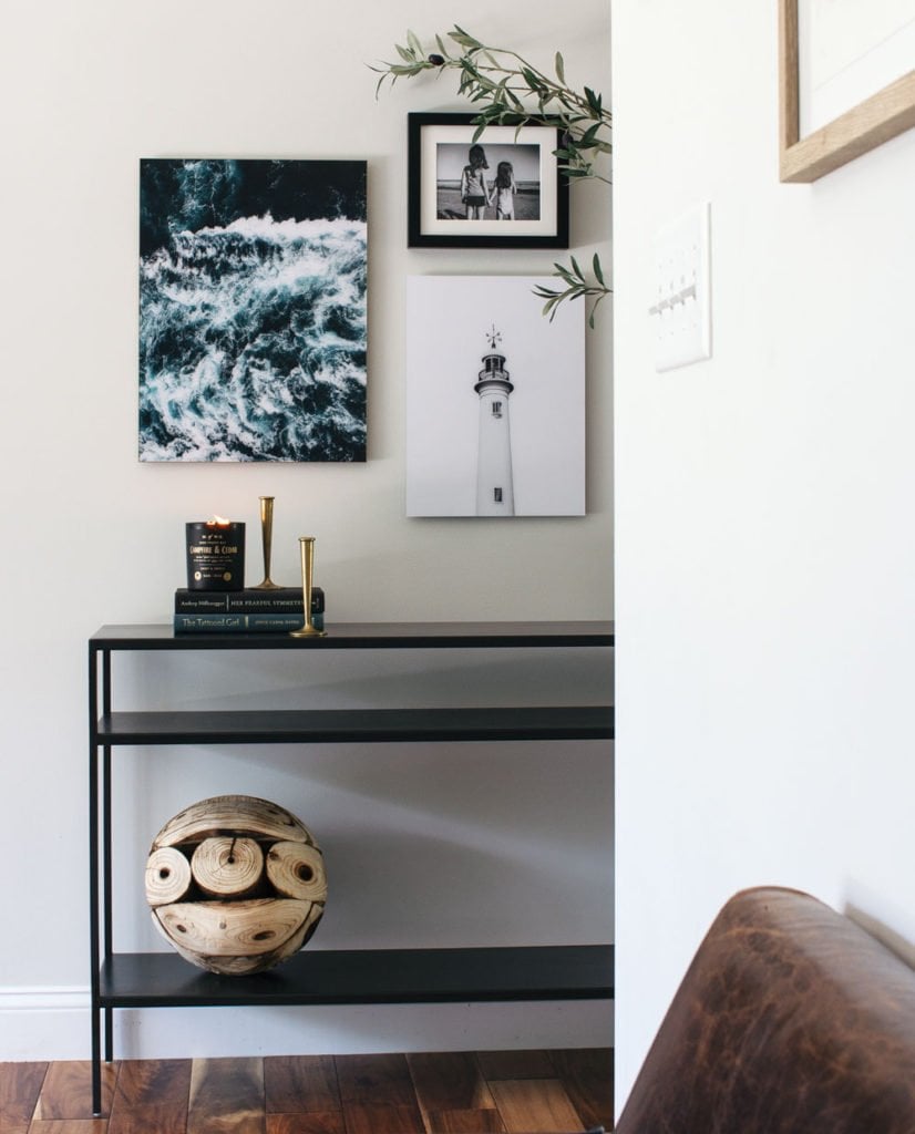 Modern entryway with coastal inspired art and a black console table.