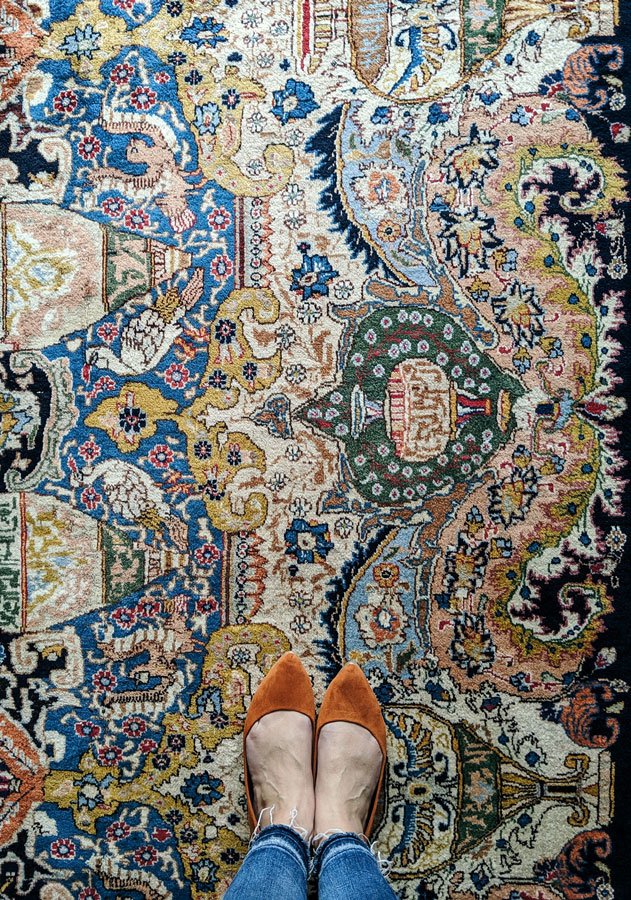 Woman in rust colored flats standing on a Persian rug .