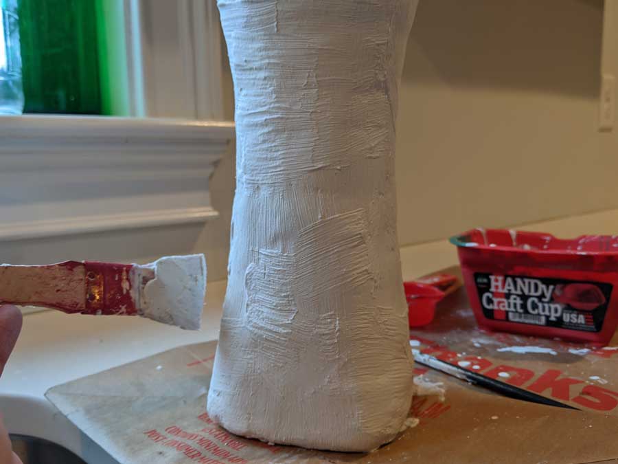 Using criss cross irregular strokes, add final layer of plaster to your faux pottery vase.