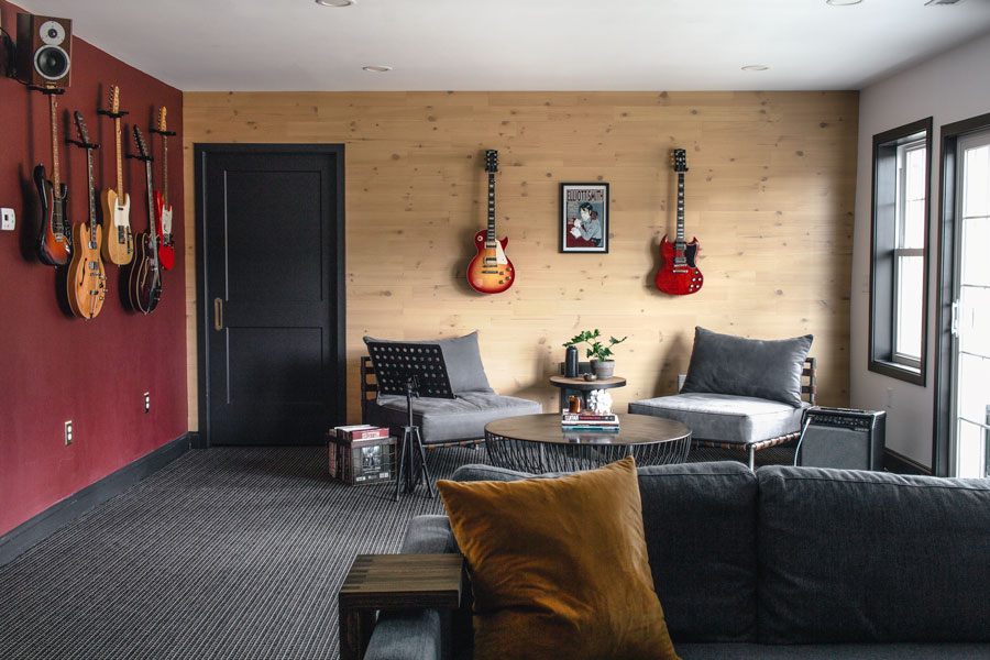 Music room with reclaimed wood wall with guitars hanging on it. Dark red accent wall.