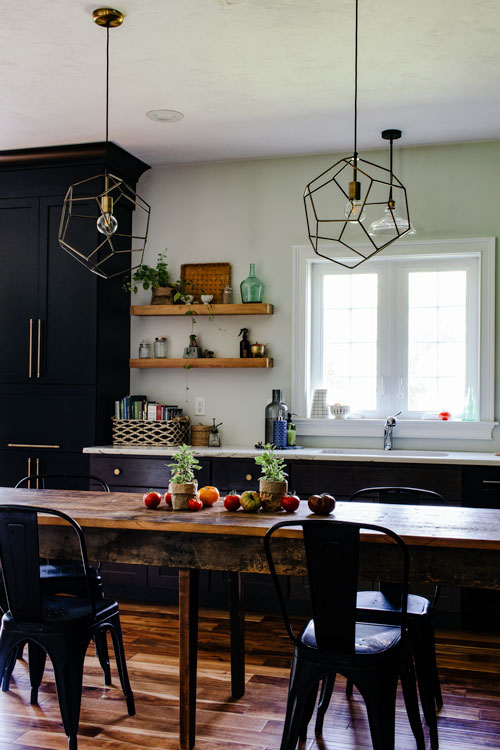 vintage farmhouse table in kitchen with black cabinets and black metal chairs