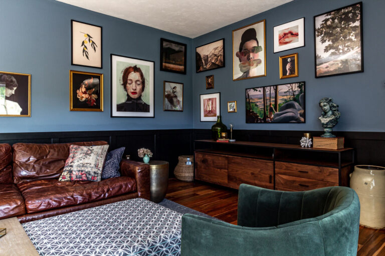 Blue and black living room with metallic side tables and gallery wall.