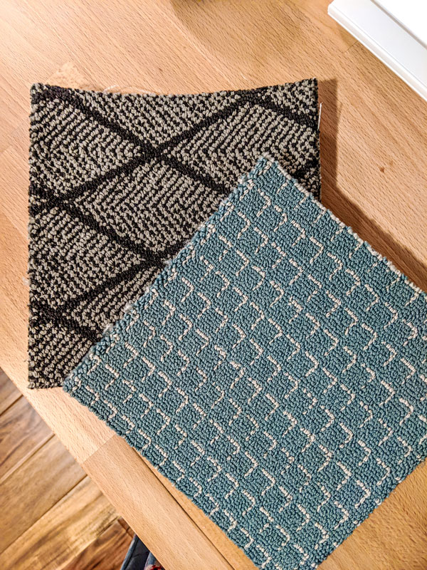 Two patterned carpet samples on a table