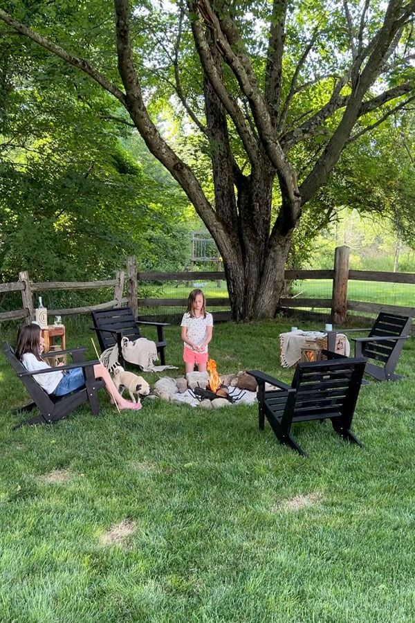 Kids sitting around backyard firepit with Adirondack chairs