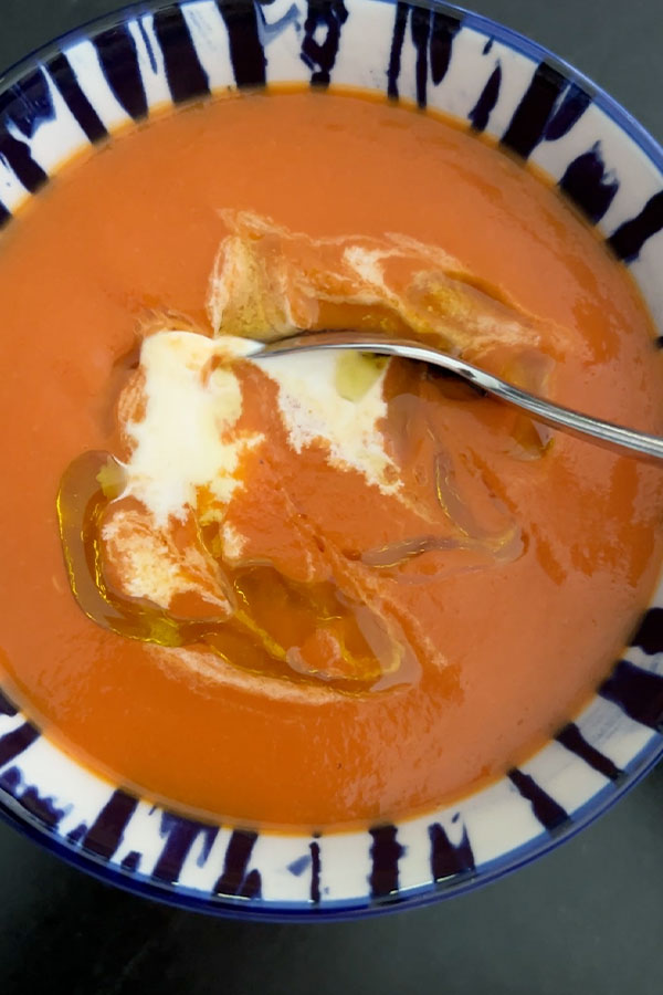 Creamy tomato soup garnished with cream and olive oil.