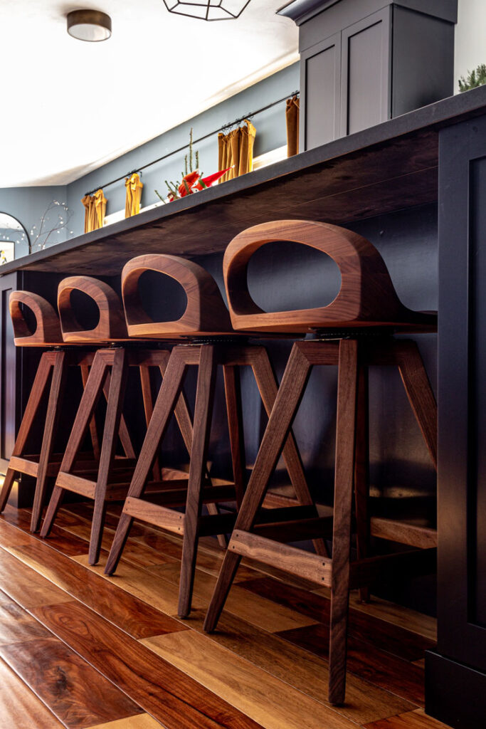 Close up of a row of walnut counter stools in front of a black island