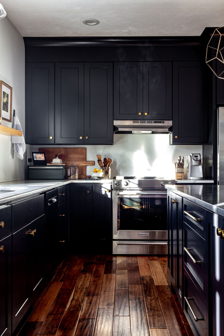 Black kitchen cabinets with white britannica quartz counters, a stainless steel oven, and black island with soapstone countertops