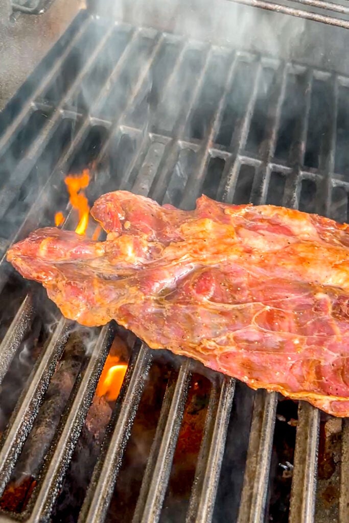 Steak cooking on a gas grill.