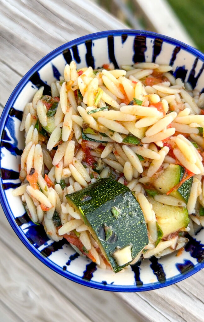 Blue bowl filled with grilled zucchini pasta salad.