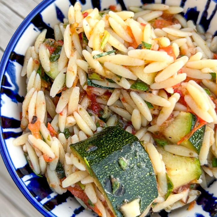 Blue bowl filled with grilled zucchini pasta salad.