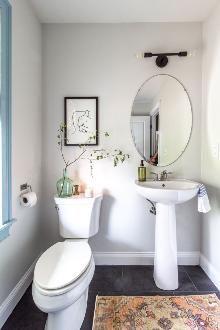 Small powder room with dark floors and white walls with blue trim.