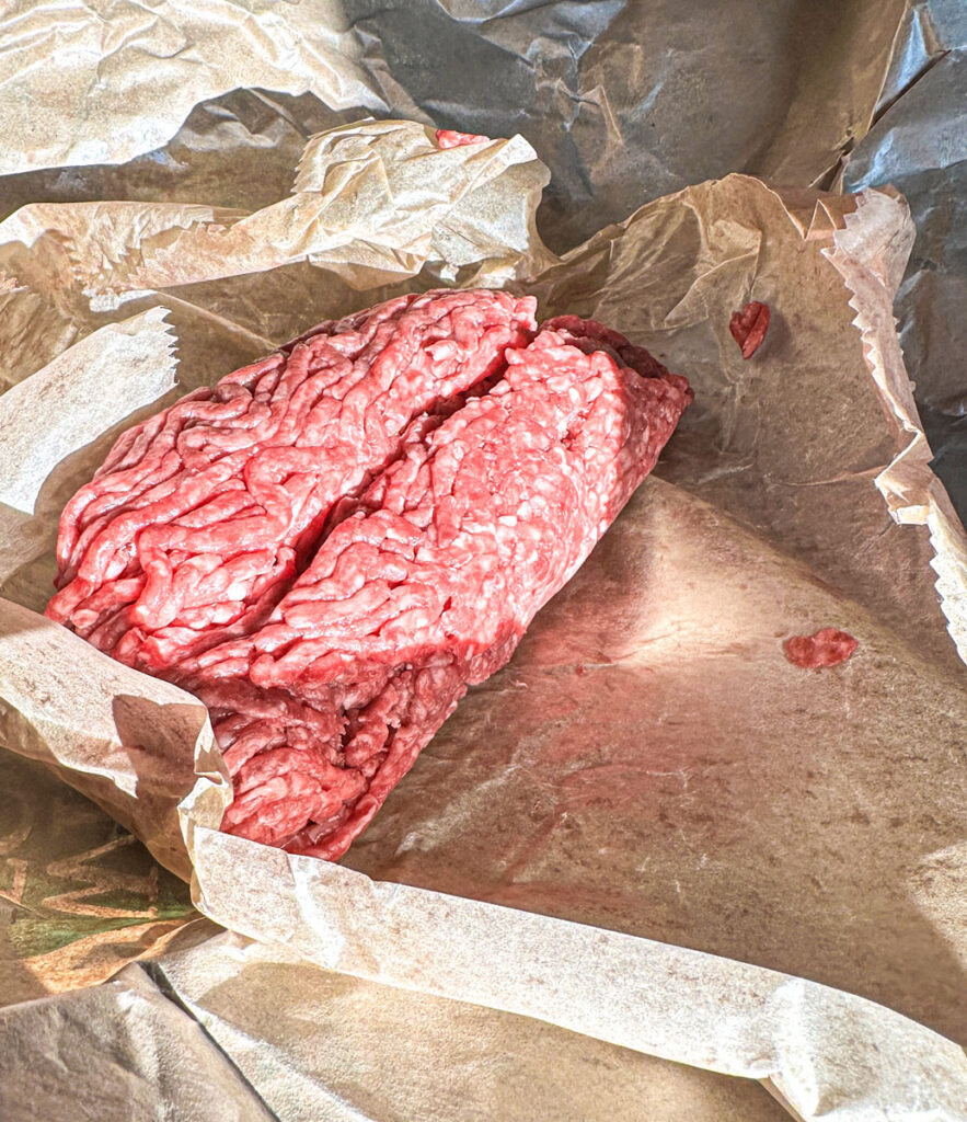 Raw ground beef on a table in an unwrapped package.