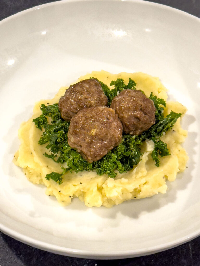 Spiced meatballs on a bed of kale salad and mashed potatoes.